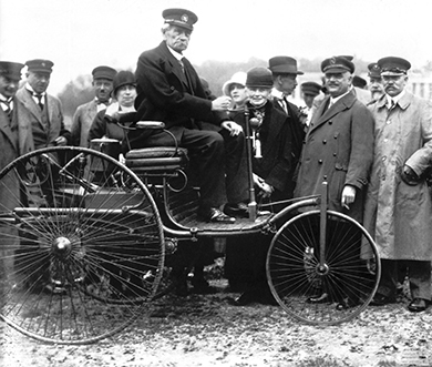 Carl Benz auf seinem ersten Patent-Motorwagen vom Typ I aus dem Jahr 1886, aufgenommen in München im Jahr 1925.